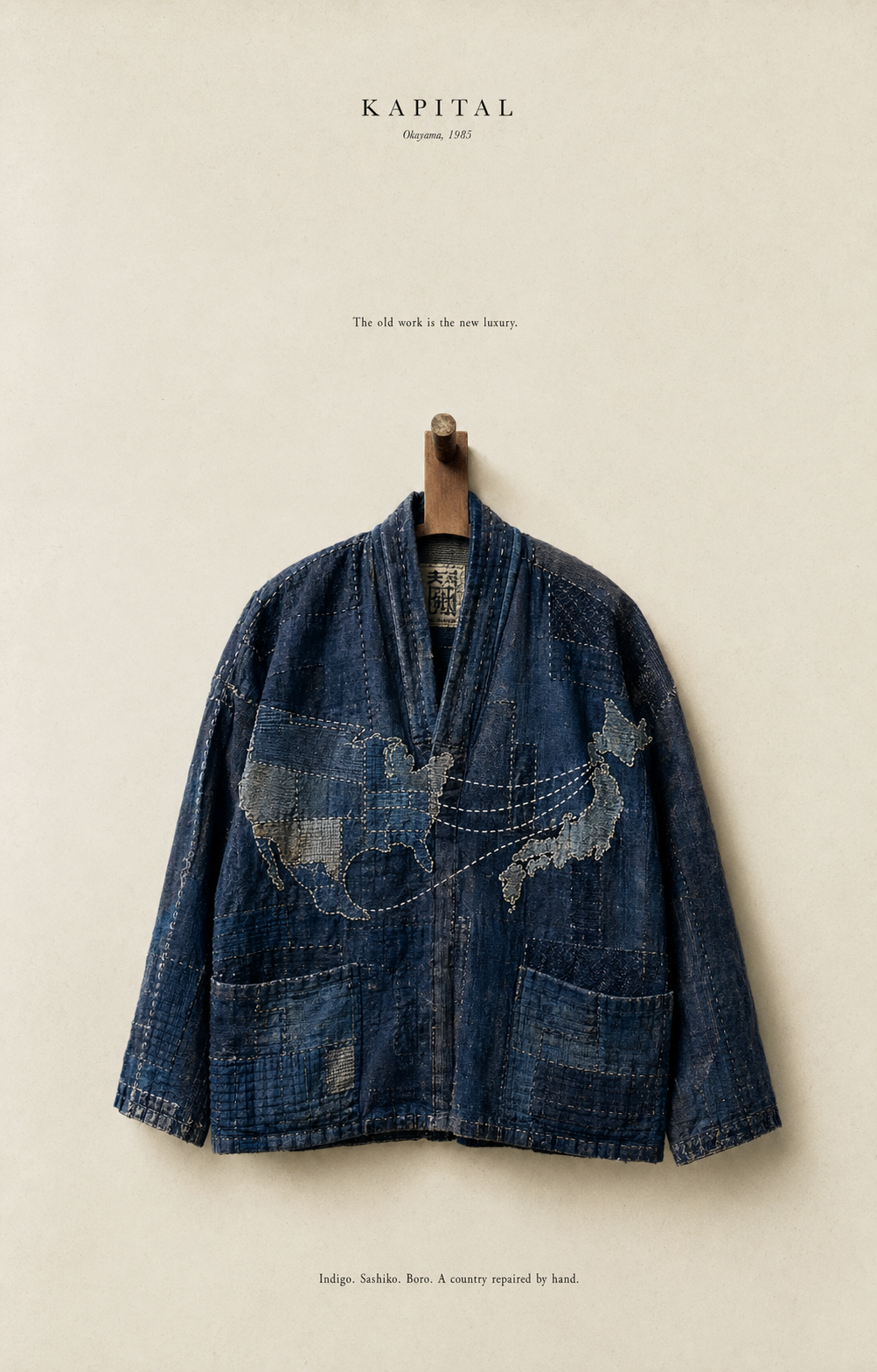A vintage indigo-dyed boro jacket on a wooden hanger, sashiko stitching forming the shape of the Japanese archipelago across the back